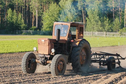 Preparing land with seedbed cultivator - tractor on field, agricultural works at farmlands, telephoto