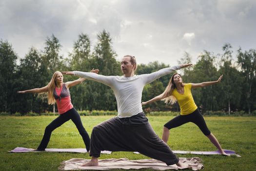 Yoga sportsmen in park - performs exercise outdoors outdoor at morning, telephoto shot