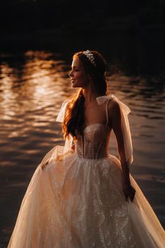 An elegant bride in a white dress enjoys nature at sunset.Model in a wedding dress in nature in the Park.Belarus.