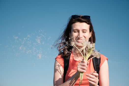 The girl blows the seeds off the dandelions.