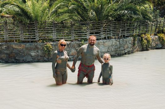 A happy family of three takes mud baths at a resort in Turkey.Family Wellness in therapeutic mud.Turkey.