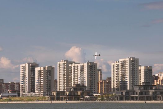 Sportive airplane flying over modern city, telephoto