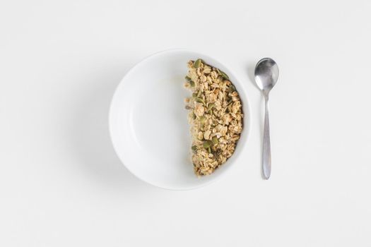 granola with pumpkin seeds white bowl spoon white background