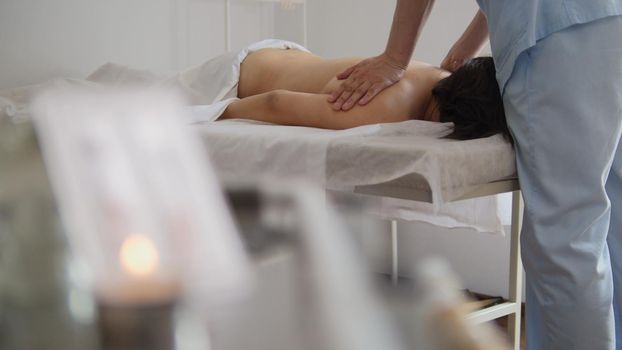 Doctor massages a woman's back in a Tibetan medicine cabinet, close-up