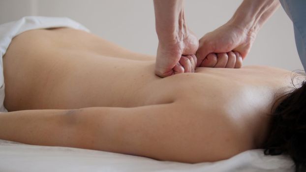 Doctor massages a woman's back in a Tibetan medicine cabinet, close-up