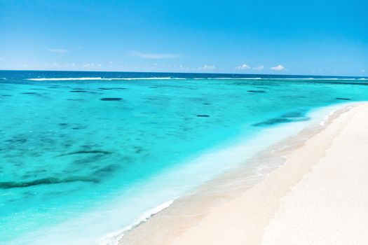 A view from a height of a Tropical beach and waves breaking on a tropical golden sandy beach. The sea waves gently wind along the beautiful sandy beach.