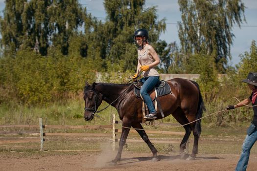 Horseback riding lessons - young woman riding a horse, telephoto shot