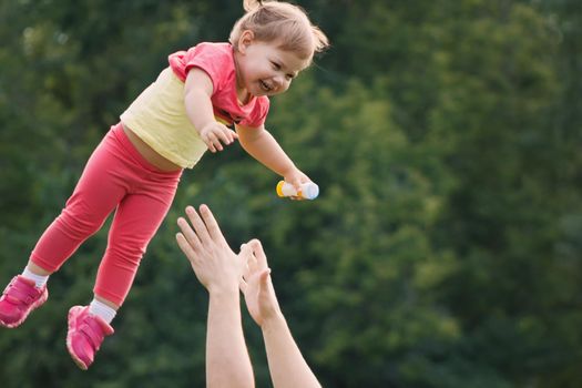 Father throwing baby girl in park, family concept