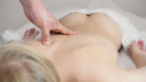 Doctor massages a woman's back in a Tibetan medicine cabinet, close-up