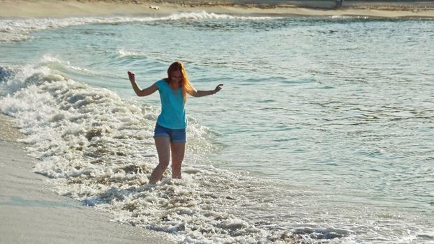 Young woman with long red hair play waves, seascape beach of Dominican Republic, Caribbean sea