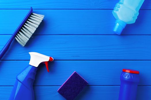 Household cleaning supplies on blue wooden background flat lay top view