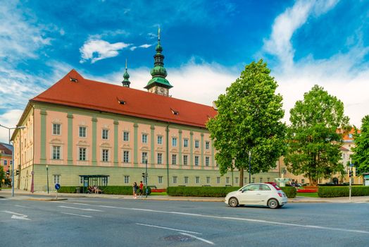 Klagenfurt - June 2020, Austria: A white car drives near the Landhaus (Country House) building in the Austrian city of Klagenfurt