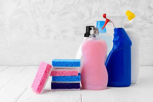 Household cleaning detergents on wooden table against gray background, close up