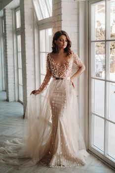 A luxurious bride in a wedding dress in the morning in her interior.