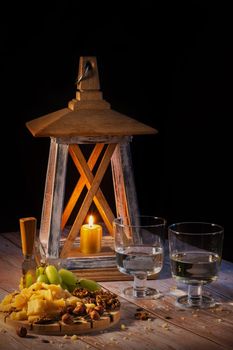 Cheese plate with a variety of snacks on the table with two glasses of wine by candlelight.