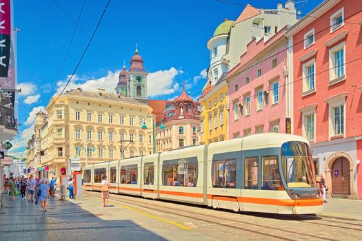 Linz - June 2020, Austria: View of the main street with walking people, a modern tram, and old colorful historical buildings