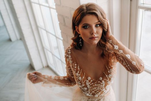 A luxurious bride in a wedding dress in the morning in her interior.