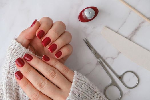 Stylish red female nails. Modern Beautiful manicure. Autumn winter nail design concept of beauty treatment. Gel nails. Skin care. Wellness. Trendy colors.