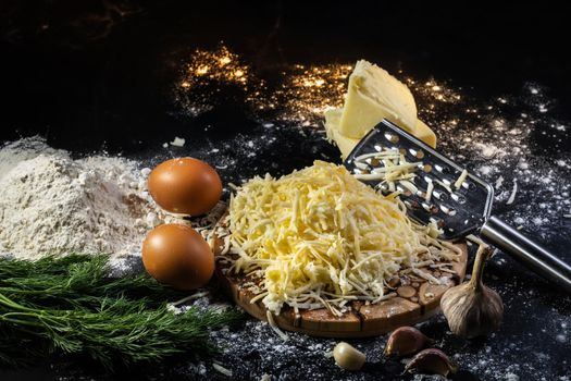 still life of the process of making cheese balls with garlic and dill on a black background.