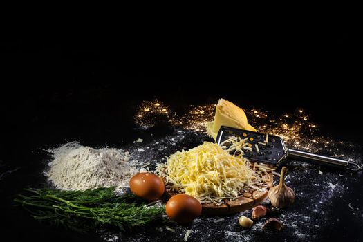 still life of the process of making cheese balls with garlic and dill on a black background.