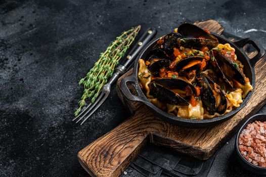 Mafaldine pasta with mussels and tomato sauce. Black background. Top view. Copy space.