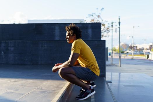 Black man with afro hair taking a break after workout at sunset.