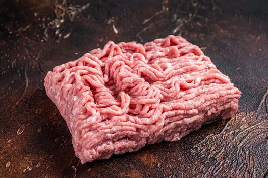 Raw ground chicken or turkey meat on brown table. Dark background. Top View.