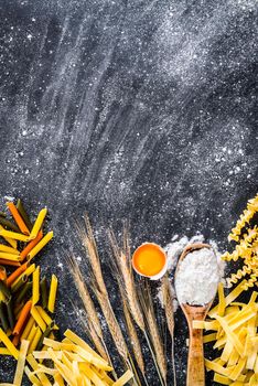 uncooked pasta, flour and other products on a black textured table