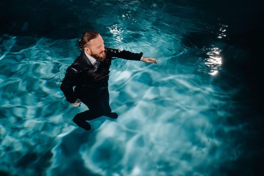 A man in a formal suit is walking in the water. A man walks on water.