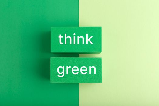 Modern minimal flat lay composition with think green inscription against green background. Concept of go green, recycle, reduce, reuse, zero waste and eco friendly lifestyle