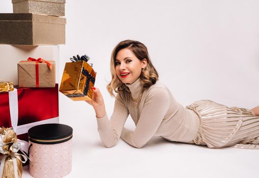 A girl in a skirt and jacket with a bunch of gifts in her hands lies on a white background.