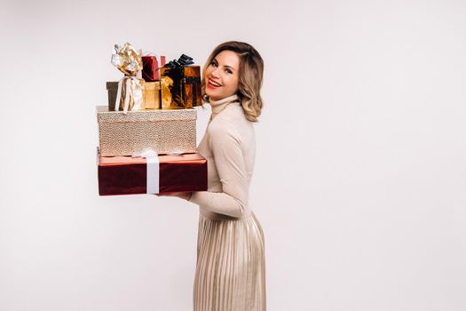 A girl in a skirt and jacket with a lot of gifts in her hands on a white background