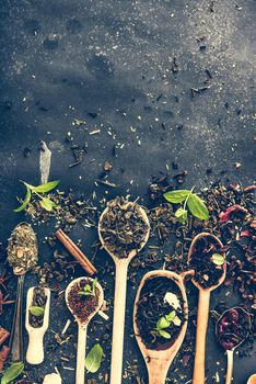 Virious kinds of tea in wooden spoons on black table