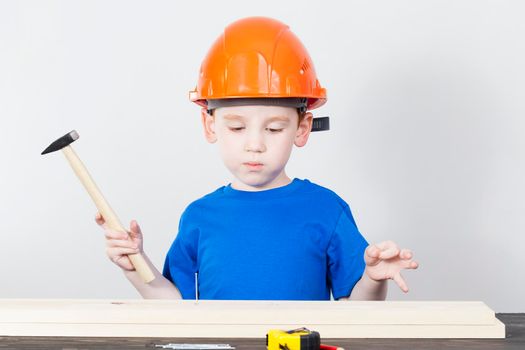 boy hammering a pine nail for their connection, color portrait closeup