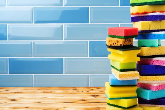 Pile of household cleaning sponges against blue tile wall background