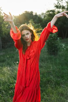 attractive woman in red dress posing in nature green grass. High quality photo