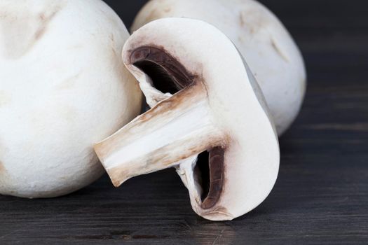 cut into half and pieces of white champignon on a black background, closeup