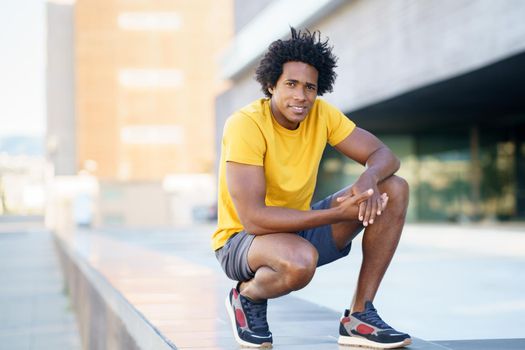 Black man with afro hair taking a break after workout outdoors.