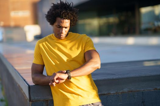 Black man with afro hair consulting his smartwatch to view his training data.