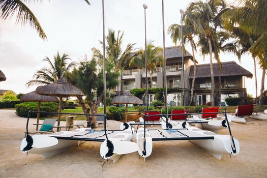 catamarans with sails are parked on the beach in front of a villa on the tropical island of Mauritius.