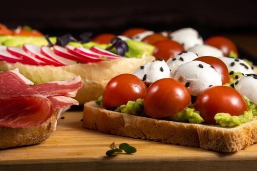 Assorted sandwiches with fish, cheese, meat and vegetables lying on the board.