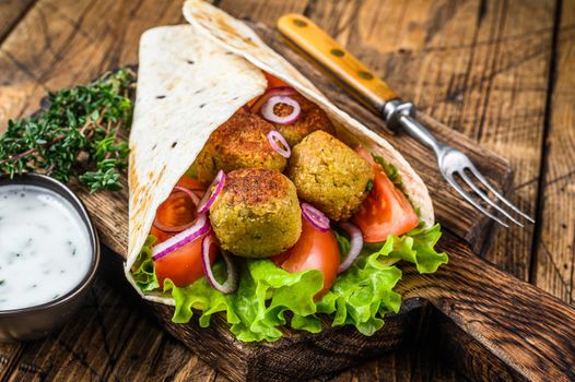 Vegetarian Tortilla wrap with falafel and fresh salad, vegan tacos. wooden background. Top view.