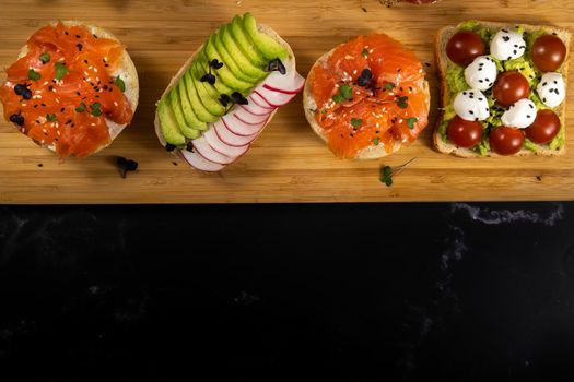 Assorted sandwiches with fish, cheese, meat and vegetables lying on the board.