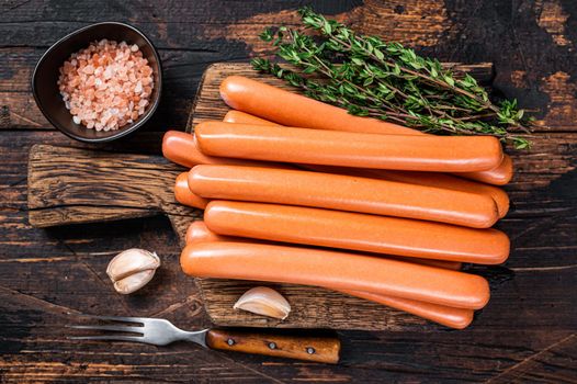 Frankfurter sausages on wooden cutting board. Dark Wooden background. Top view.