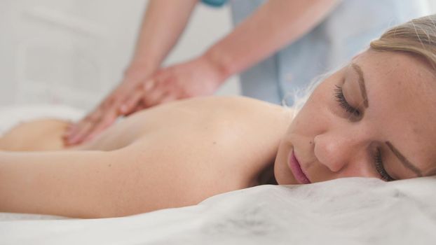 Attractive young woman receiving massage at spa. Relaxation treatment for shoulders, medicine close up