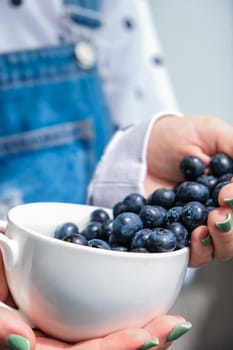 Woman holding bowl with fresh blueberries. Harvesting concept. Female hands collecting berries. The concept of vegetable garden cottage harvest gardening. Healthy eating nutrition