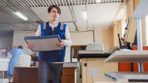 Printing process - worker inserts paper sheets, wide angle