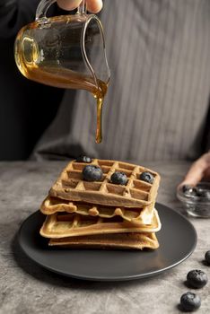 high angle man pouring syrup stack waffles