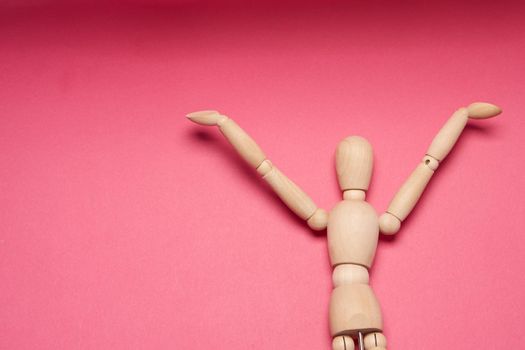 wooden mannequin on pink background posing close-up. High quality photo
