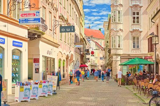 Steyr - June 2020, Austria: The main street with beautiful colorful buildings in the traditional architectural style and people sitting in the bar and strolling enjoying the beautiful day